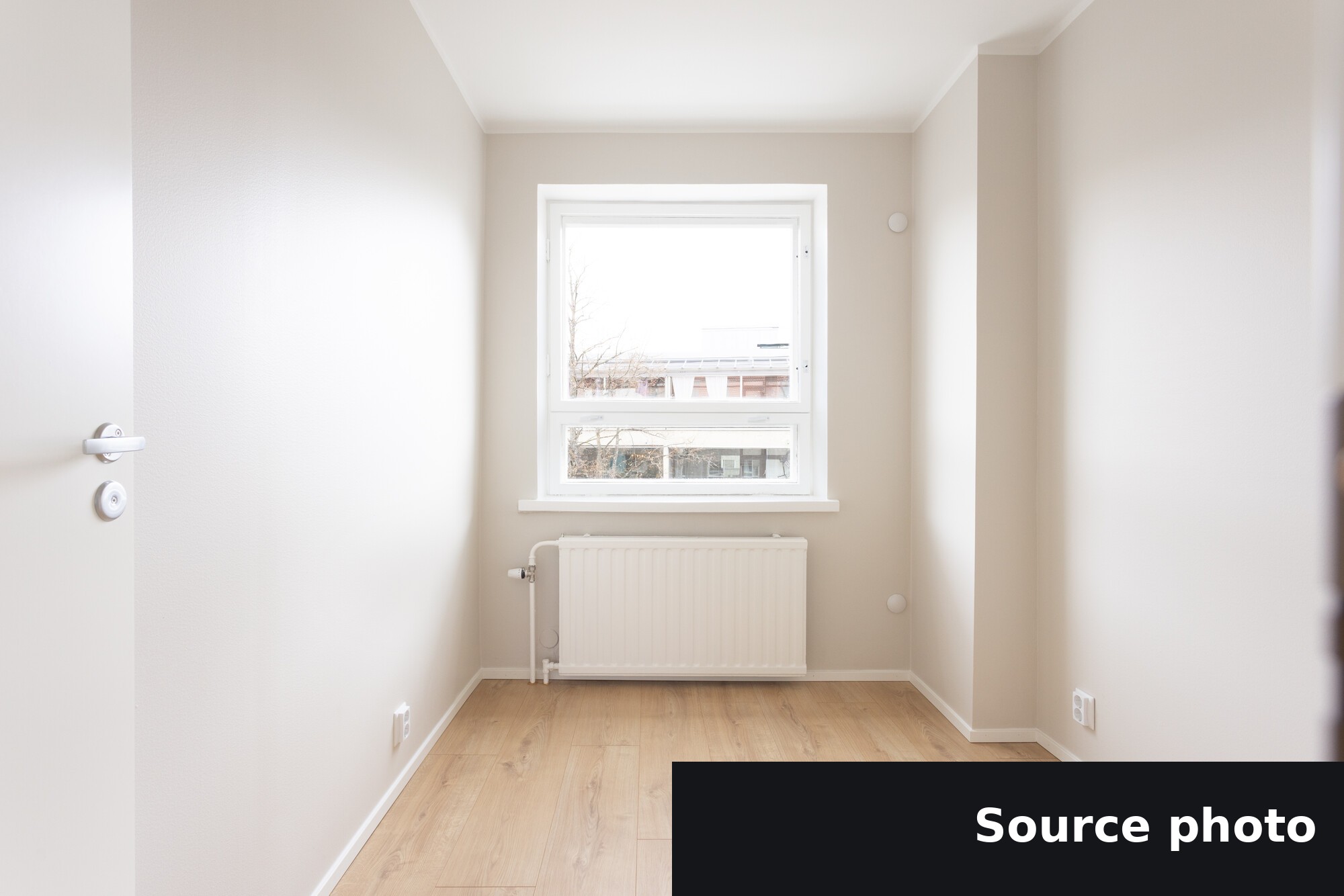 An empty narrow room with a window and radiator, the original listing photo.