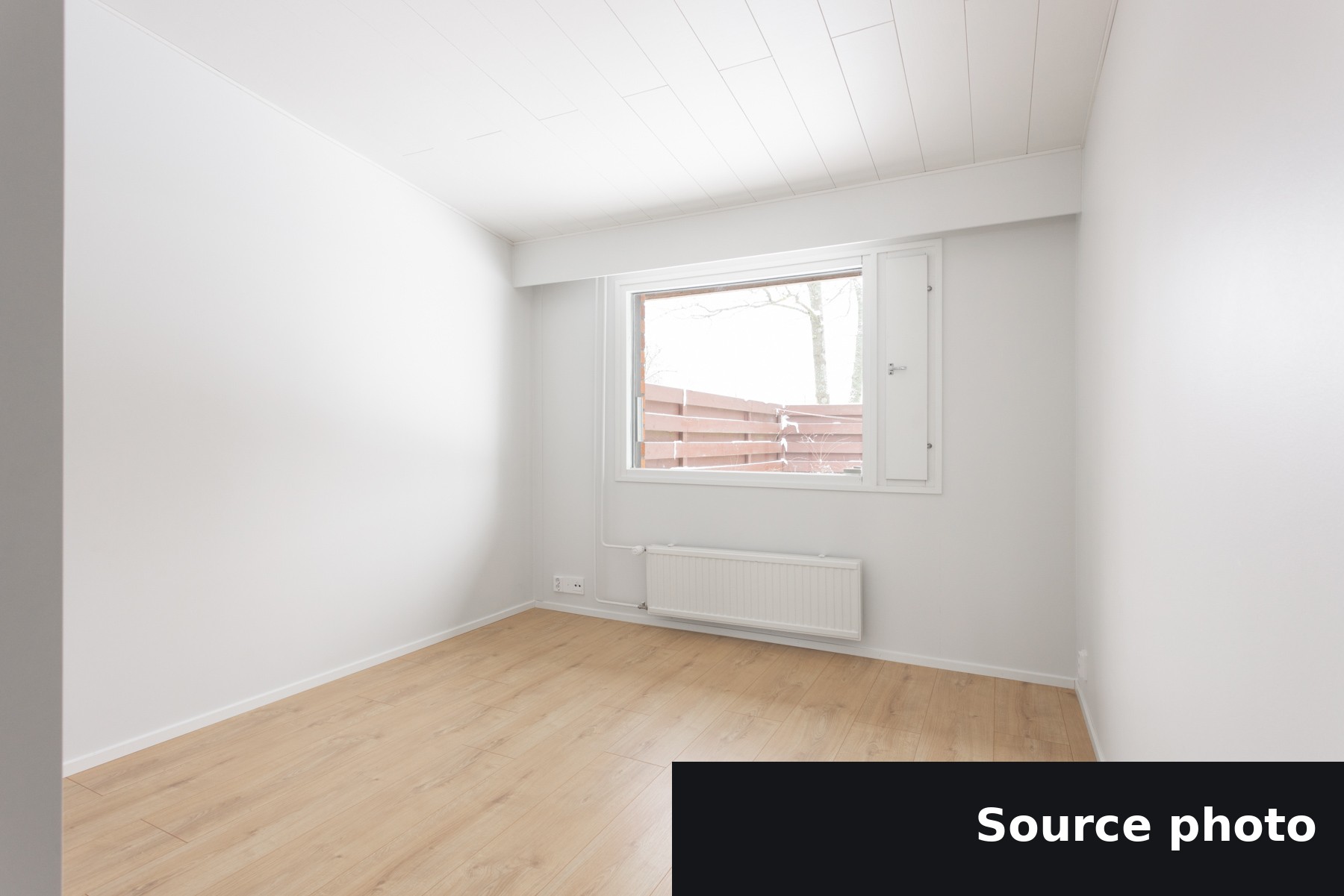 An empty bedroom with a single window, the original listing photo.