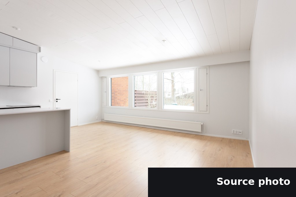 An empty open-plan room next to a kitchen counter, the original listing photo.