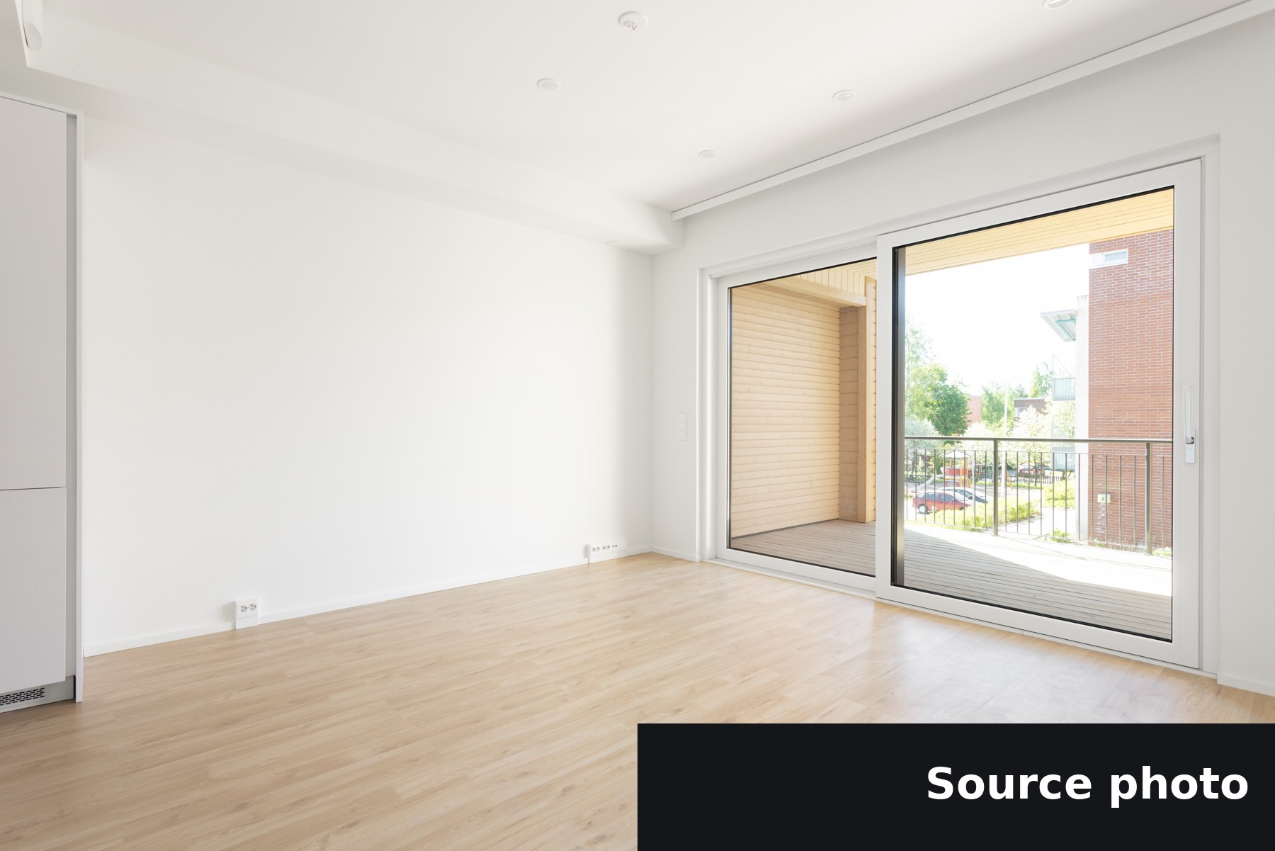 An empty living room with a balcony door, the original listing photo.