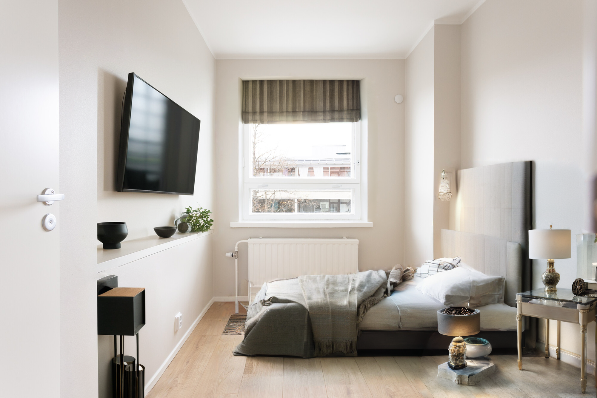 The narrow room furnished object by object with a bed and side table.